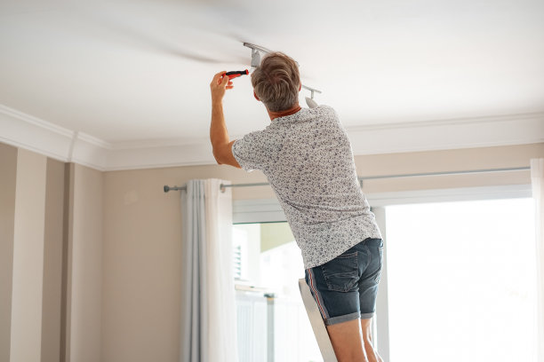 成熟有经验的电工在楼梯上给家里的天花板安装桨扇图片下载