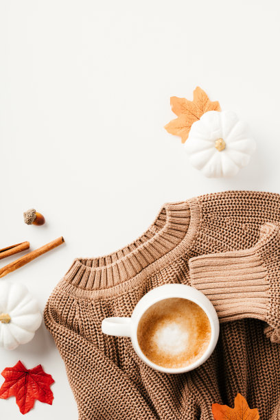 秋平以毛衣和咖啡杯、树叶、白色背景装饰的南瓜构成图片下载