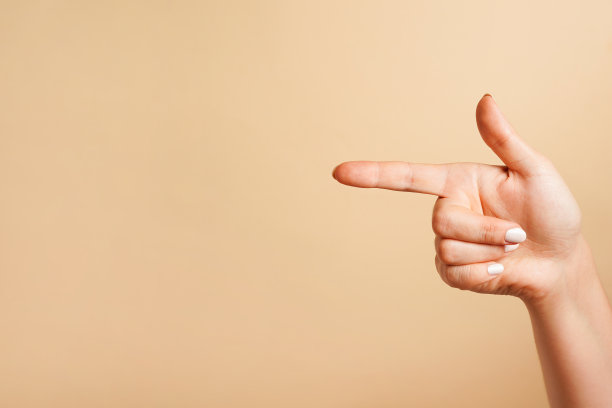一个食指指向一个位置，米色背景与复制空间图片下载