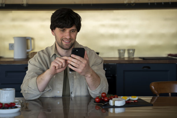 男子早上在厨房用智能手机工作图片下载