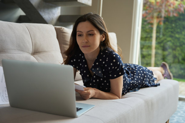穿着居家装的女人躺在沙发上，手里拿着笔记本电脑图片下载