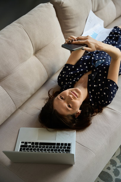 女性在笔记本电脑旁边用手机在线交流图片下载