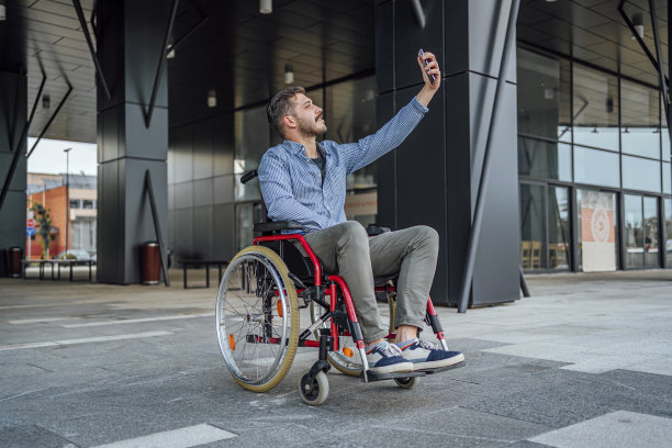 坐在轮椅上的快乐男子在户外自拍图片下载