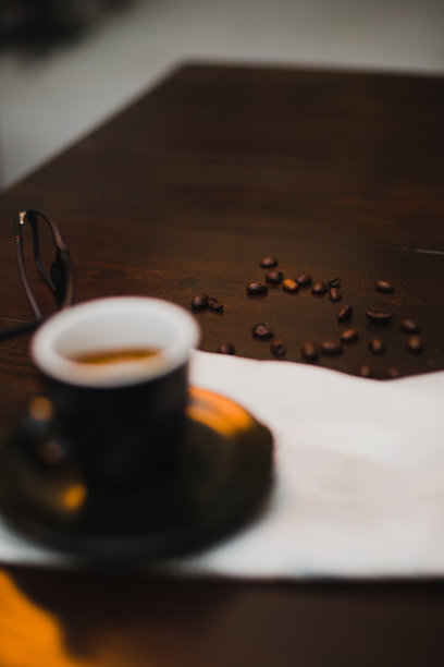 黑咖啡杯里的新鲜咖啡，木桌上的咖啡豆图片下载