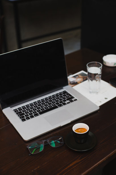 现代的工作场所，笔记本电脑，一杯新鲜的咖啡，一杯水和木桌上的玻璃杯图片下载