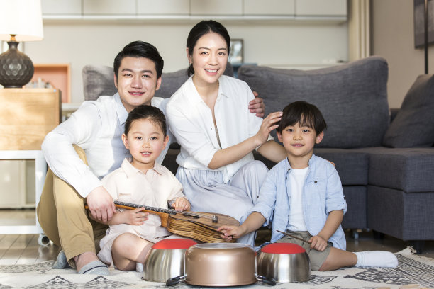 一个男孩和一个女孩坐在地毯上，调皮地在尤克里里琴和厨房用具上玩耍，而父母们则欣喜地欣赏着这张照片图片下载