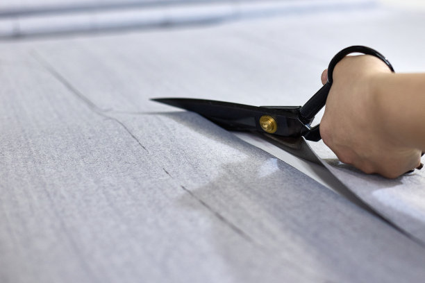 裁缝在缝纫车间用剪刀裁剪布料的特写图片下载