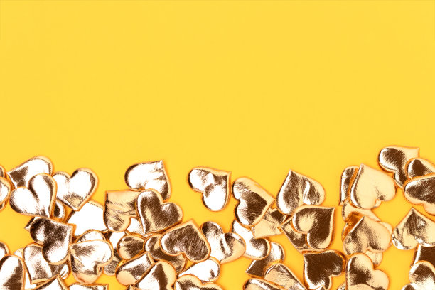 粉红色背景上的金色心形纸屑。图片下载