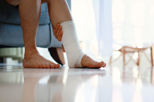 一位老年妇女的腿部特写，用绷带保护扭伤的脚踝和肿胀的脚。图片下载