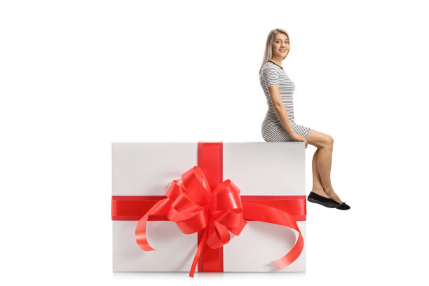 年轻女子坐在一个大礼物盒上图片下载