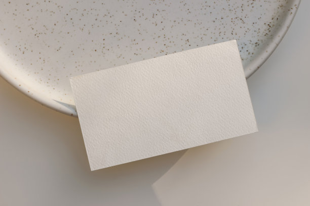 夏季品牌文具。特写纹理空白名片，邀请模型上的点，斑点陶瓷板在阳光下。米色的桌子背景。优雅的平面布局，俯视图。没有人。图片下载