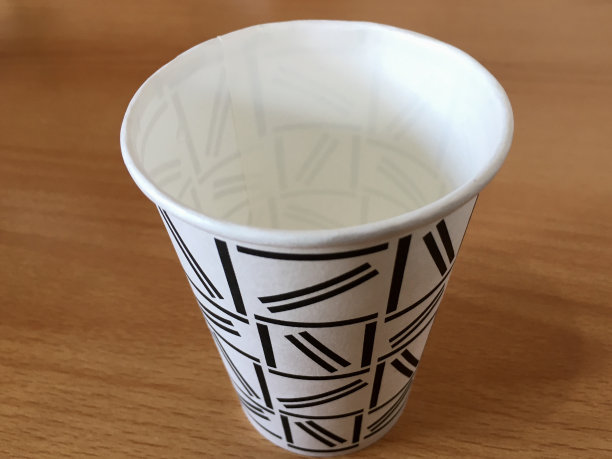 木桌上的白色玻璃杯上有黑色的涂鸦图片下载