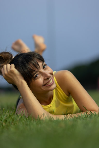 傍晚时分，年轻女子躺在草地上。图片下载