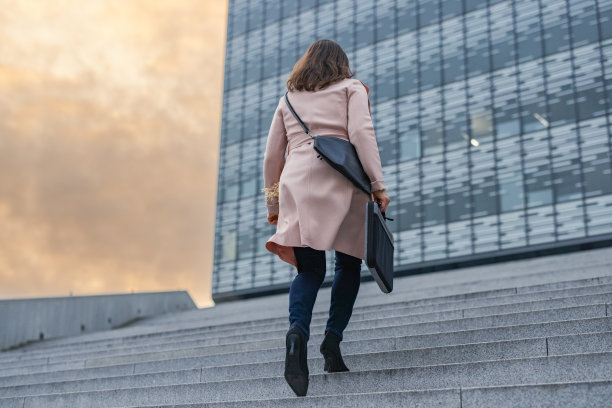 女商人提着公文包和钱包爬上楼梯图片下载