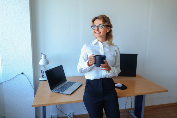 一个女商人在办公室工作时喝咖啡的照片。图片下载
