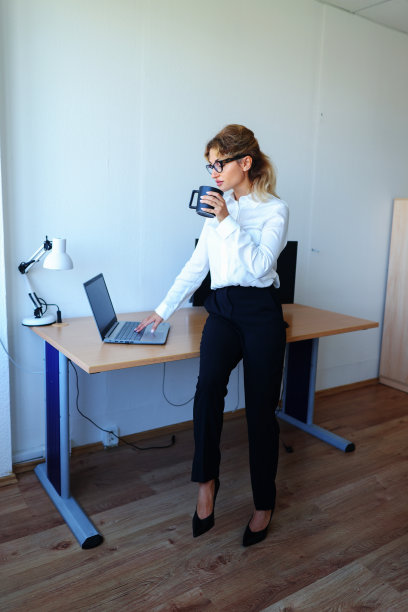 一个女商人在办公室工作时喝咖啡的照片。图片下载