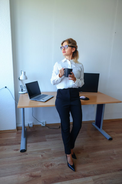 一个女商人在办公室工作时喝咖啡的照片。图片下载