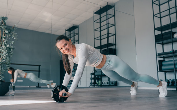 身穿运动服的黑发开朗的年轻女子在做腹部运动。健康的白人女孩提高身体的耐力，快乐的健身模特在锻炼，看起来空中镜头牙齿微笑。图片下载