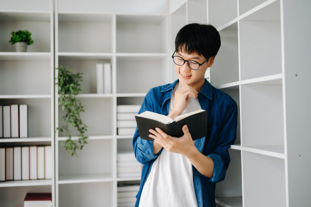 男学生在图书馆记笔记，年轻的亚洲人在大学图书馆坐在书桌前做作业图片下载