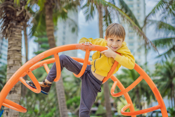 男孩在操场上爬，背景是棕榈树图片下载