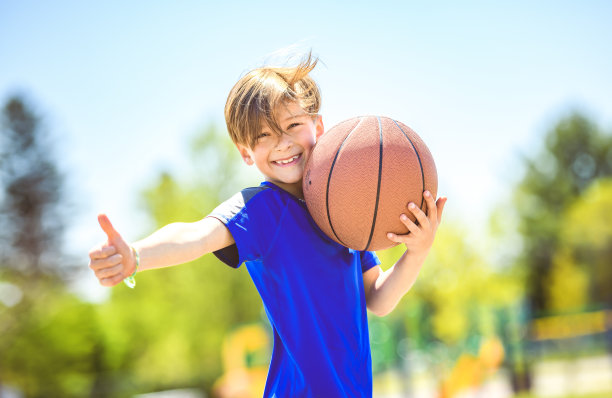 一个小男孩在公园里打篮球的照片图片下载