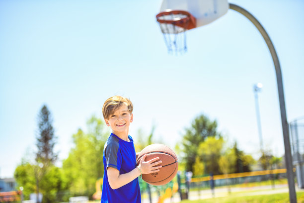 一个小男孩在公园里打篮球的照片图片下载