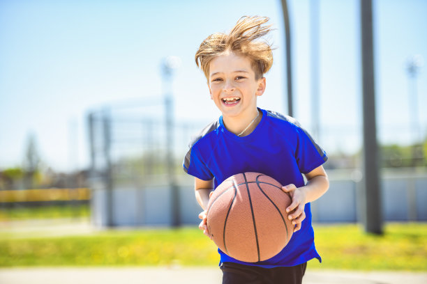 一个小男孩在公园里打篮球的照片图片下载