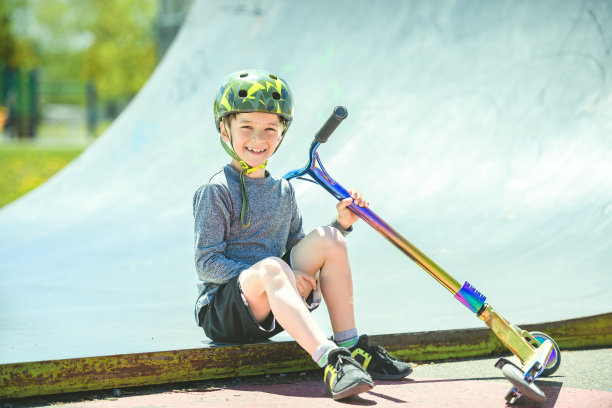 一个戴着头盔的男孩在阳光明媚的日子里骑着他的摩托车图片下载