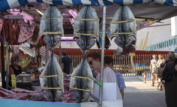 一位老妇人在鱼市购物。图片下载