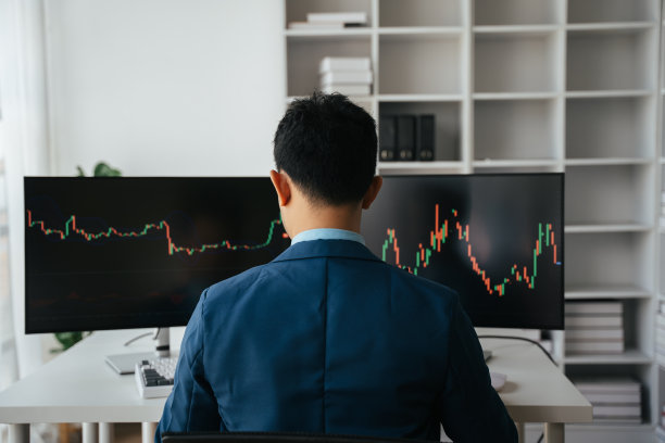 年轻的商人双手捂着脸坐在创意办公室的办公桌前，股票市场的概念。图片下载