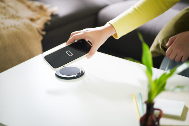 用桌上的无线充电装置给手机电池充电。智能手机在充电板上充电。手机附近无线充电器现代生活科技理念。图片下载