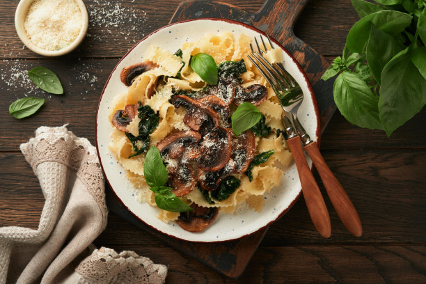 奶油阿尔弗雷多意大利面。意大利面，蘑菇，鸡肉，菠菜，罗勒和奶油酱在古老的乡村餐桌背景。传统的意大利菜。平的。本空间图片下载