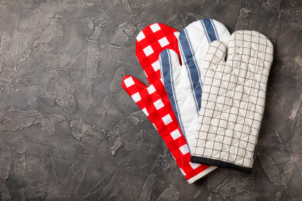 木制厨房用具，砧板，锅座和手套在桌子上，俯视图。厨房手套和烤箱防护手套放在桌上。厨房用具。厨房accessories.Close-up。前视图。图片下载