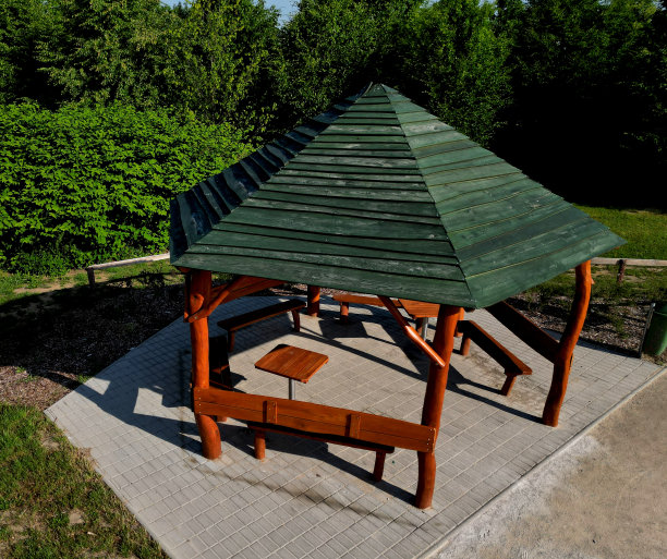 多边形的藤架，周围有长凳和栅栏。里面空间很大。屋顶呈金字塔形，覆盖着沥青瓦，在自然公园，人行道，砾石图片下载