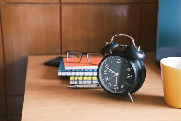 咖啡杯，笔记本电脑和桌子上的时钟靠近图片下载