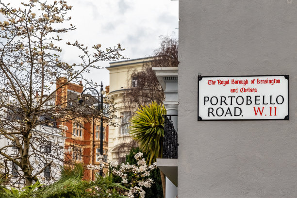 波多贝罗路的街道标志在灰色的墙上，有住宅楼和公园。诺丁山，英国伦敦。图片下载