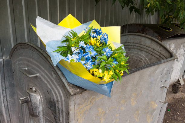 扔在垃圾桶里的花束。鲜花束在垃圾旁。破碎的爱情概念图片下载