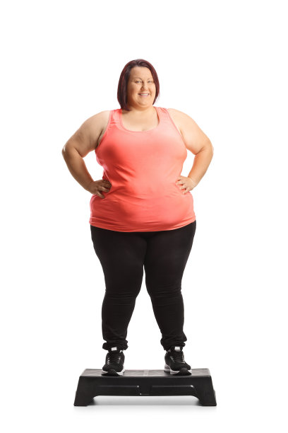 一个微笑的胖女人站在台阶有氧平台的全身肖像图片下载