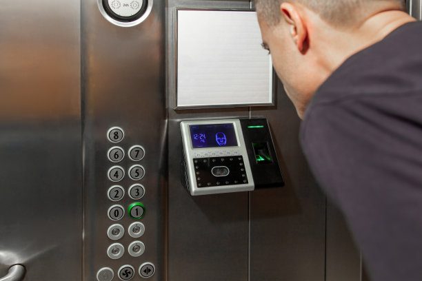 一名男子向安装在电梯里的指纹门禁终端展示自己的脸，该终端具有面部识别功能图片下载