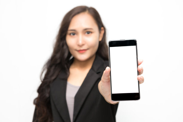 选择性聚焦智能手机在亚洲商业女性手穿黑色西装呈现一些东西在白色背景和复制空间。自信的亚洲职业女性微笑，开朗图片下载