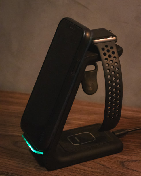 木制办公桌子与电话和智能手表充电器。侧视图图片下载