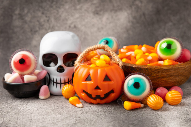 玉米糖的纹理背景。万圣节的概念。一桶万圣节南瓜南瓜灯和玉米糖庆祝万圣节。南瓜脸上带着可怕的微笑。糖果桶。图片下载