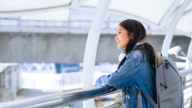 年轻的亚洲女子用耳机听好听的音乐，在城市里散步。女孩幸福，笑脸迎人。女性喜欢听让她放松和享受生活的音乐图片下载