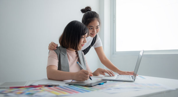 团队设计师使用笔记本电脑设计时尚服装。图片下载