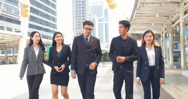 一群商务人士亚洲团队伙伴一起走在城市快乐。领导行政人员以自信的团队精神屹立于现代都市。肖像多元化商人团队合作图片下载