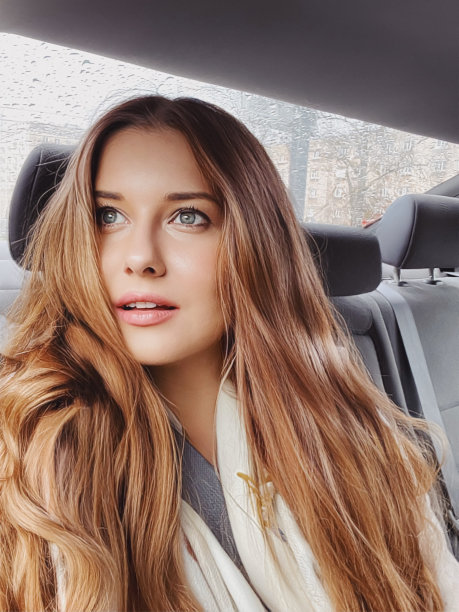 年轻女子长头发，波浪发型在汽车或出租车作为乘客，探索城市，交通和旅行图片下载