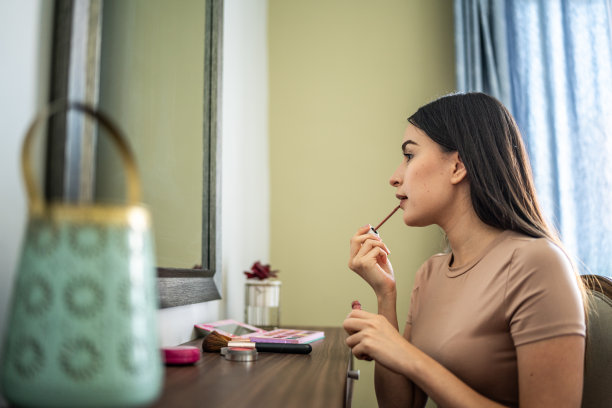 年轻女子在家里的卧室里化妆图片下载