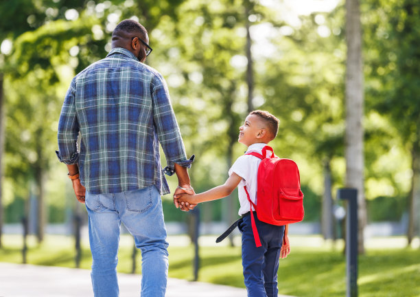 一个秋高气爽的日子，一个男生和爸爸一起去上小学一年级，他微笑着看着爸爸图片下载