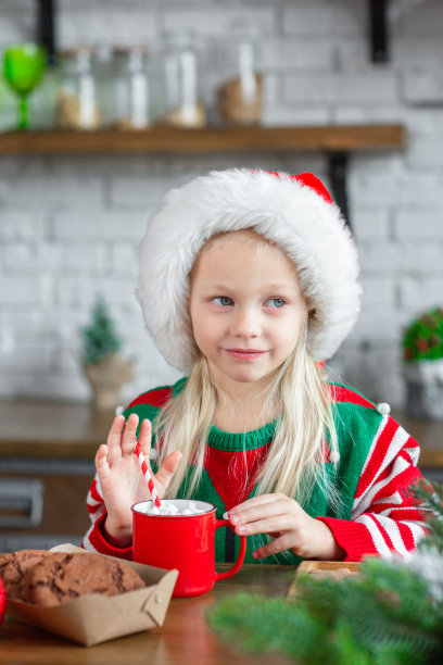 可爱的小女孩吃着甜饼干，喝着热可可图片下载