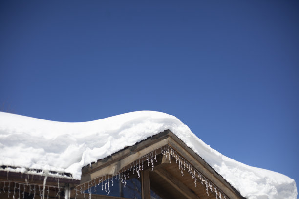 白雪覆盖的屋顶。在山区滑雪胜地的旅馆。建筑物建在高山上。图片下载